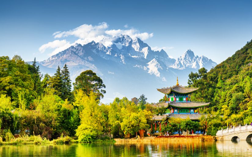 Scenic view of the Jade Dragon Snow Mountain and the Moon Embracing Pavilion on the Black Dragon Pool in the Jade Spring Park, Lijiang, Yunnan province, China.