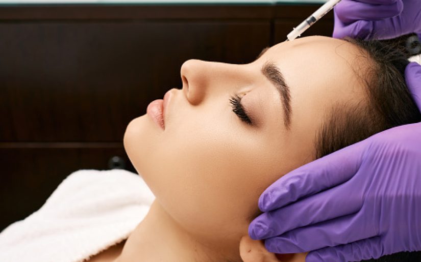 Botulinum toxin injections to beautiful woman's forehead, side view. Anti-aging procedure after 30 years, cosmetologist doing beauty injection