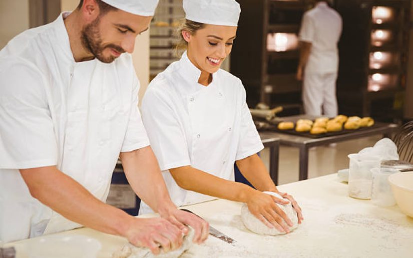Team of bakers kneading dough in a commercial kitchen