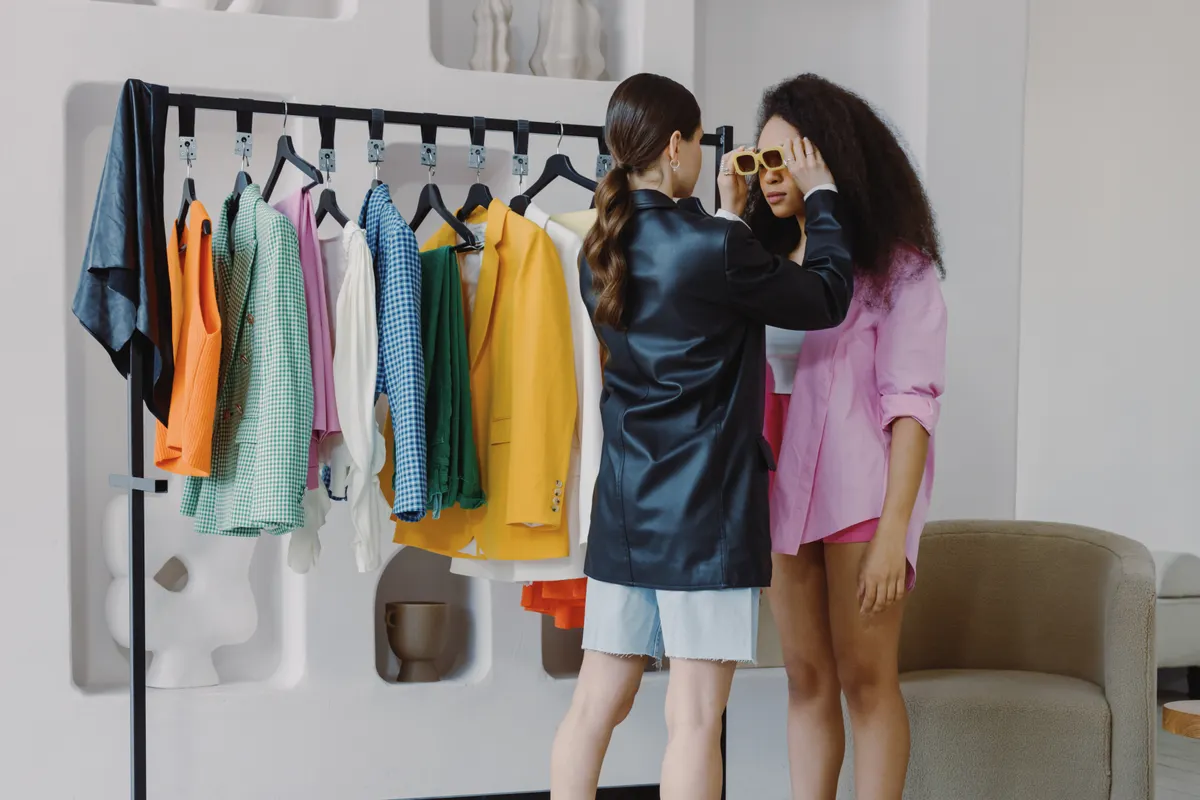 Fashion stylist assists client in a vibrant wardrobe fitting, ensuring perfect accessory choices