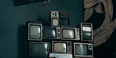 A stack of vintage CRT televisions in a dimly lit modern room with abstract art