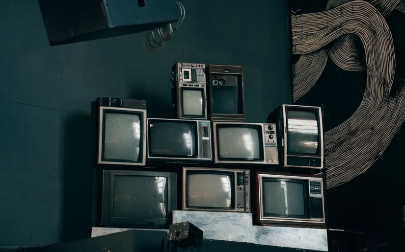 A stack of vintage CRT televisions in a dimly lit modern room with abstract art