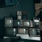 A stack of vintage CRT televisions in a dimly lit modern room with abstract art