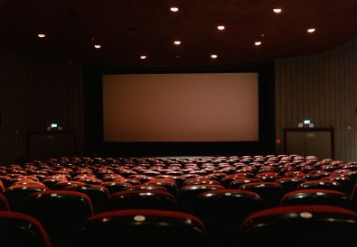 An empty cinema auditorium facing the screen, where adaptations and remakes reach audiences