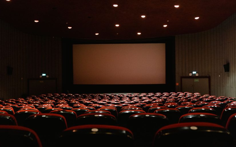 An empty cinema auditorium facing the screen, where adaptations and remakes reach audiences